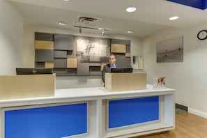 A reception desk with a modern design, a clock on the wall, and a framed picture. - Holiday Inn Express Hotel & Suites Dayton-Centerville by IHG (Dayton)