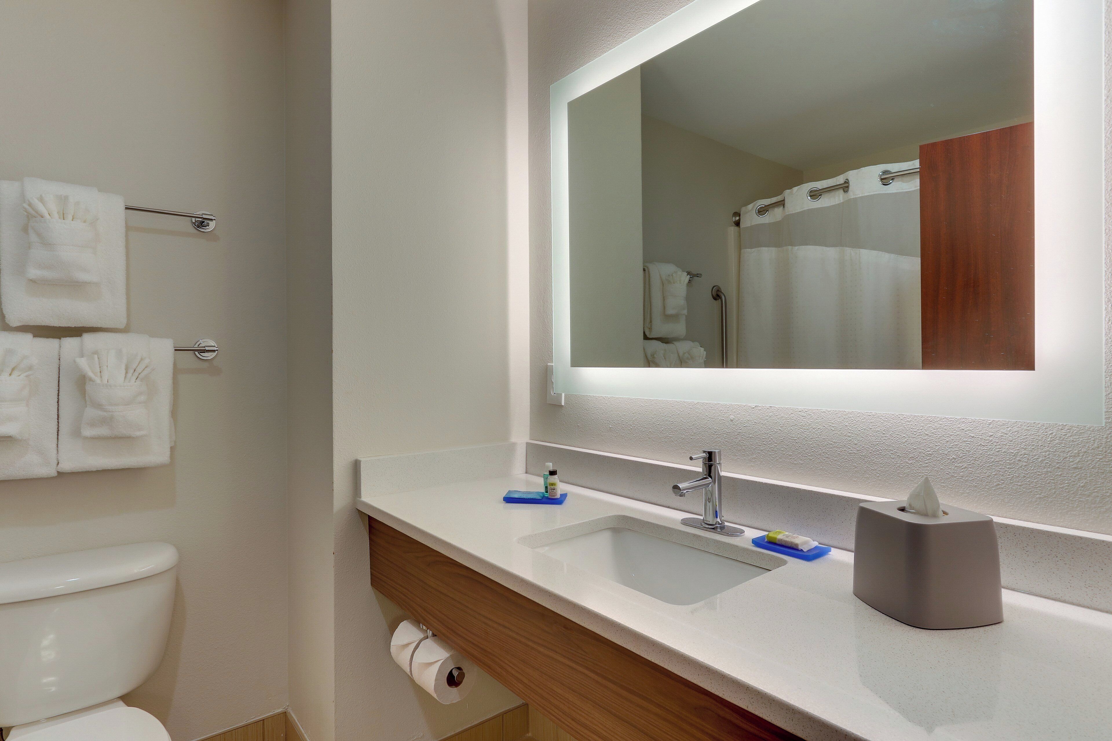 A bathroom with a white sink, a mirror, a towel rack, and a toilet.