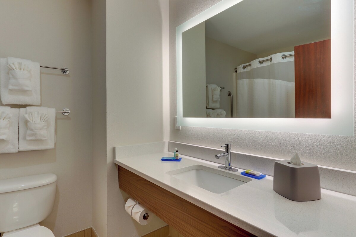 A bathroom with a white sink, a mirror, a towel rack, and a toilet.
