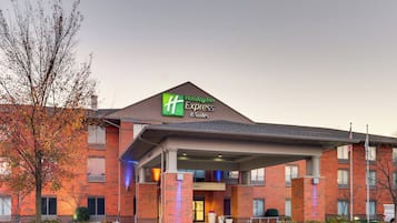 Edifício da Holiday Inn Express & Suites com fachada de tijolos, entrada coberta e estacionamento.