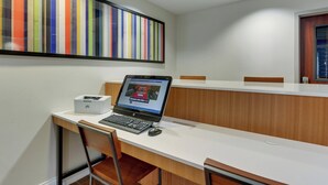 Un espace de bureau moderne avec une grande table blanche, un ordinateur portable et une imprimante HP.