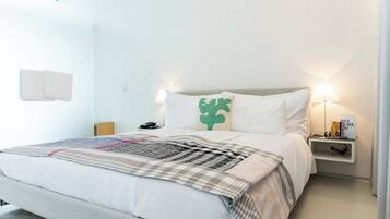A neatly made bed with a checkered blanket, a bedside lamp, and a nightstand with a phone and a decorative item.