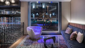 Un interior moderno con una zona de estar, una alfombra estampada y un ventanal con vistas a un edificio.
