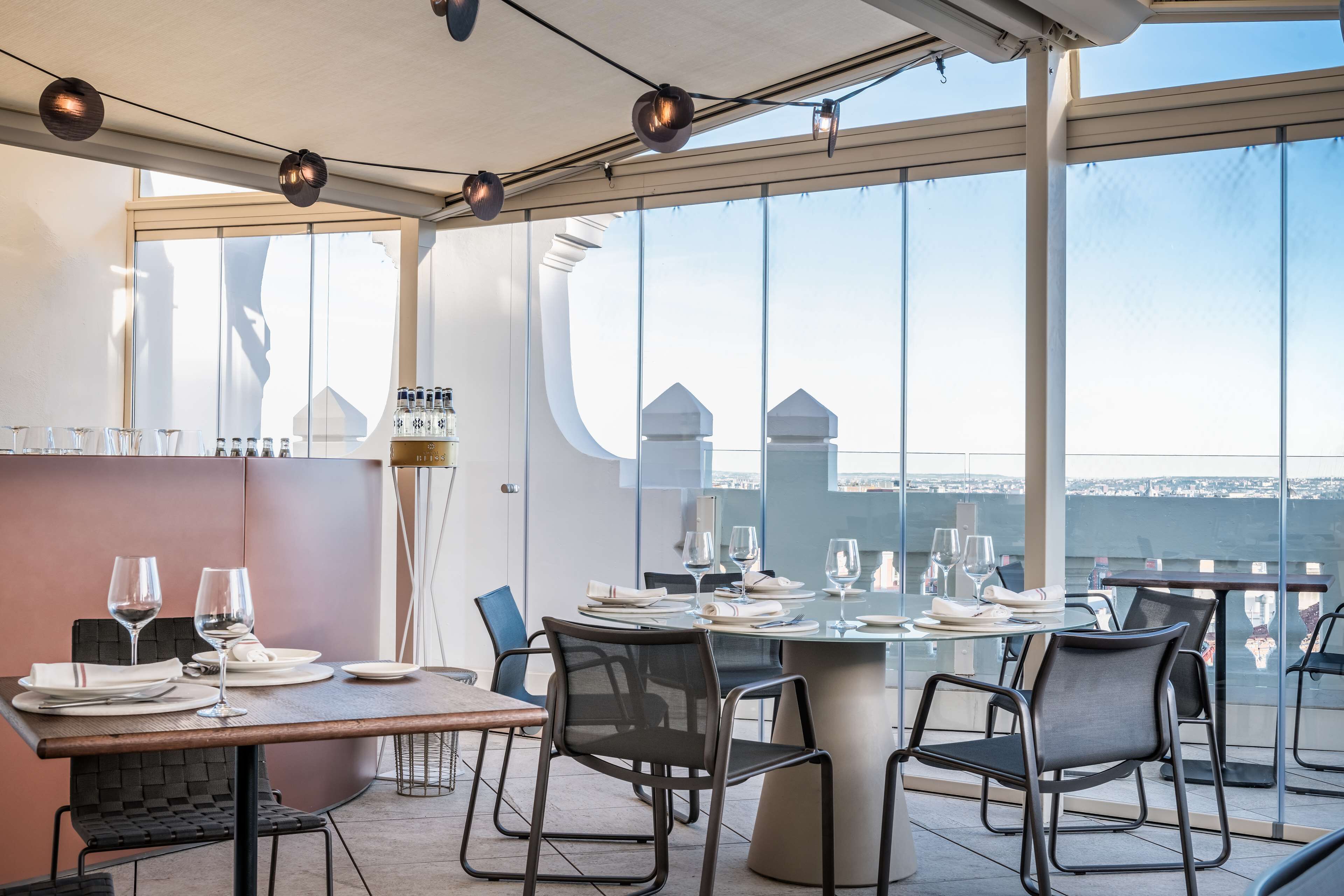A dining area with a table set for two, large windows, and a view of a cityscape.