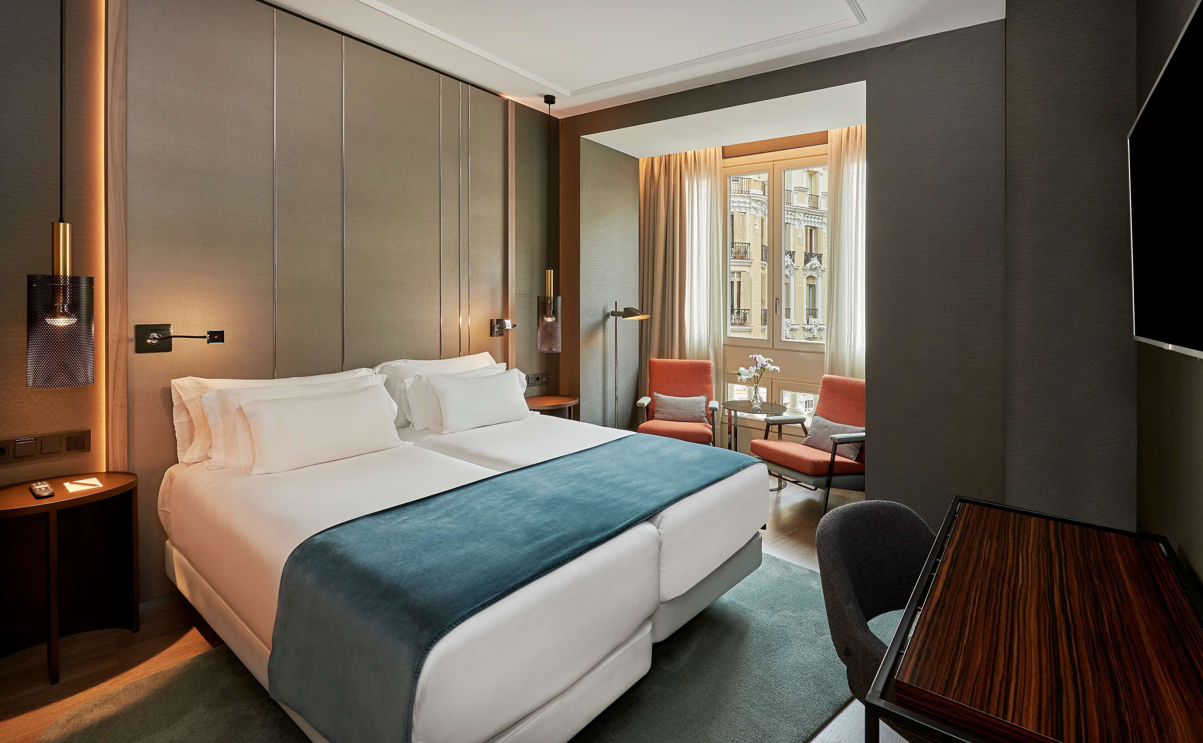 Una habitación de hotel con una cama grande, un escritorio, una silla y un televisor.