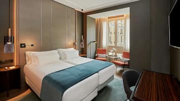 Una habitación de hotel con una cama grande, un escritorio, una silla y un televisor.