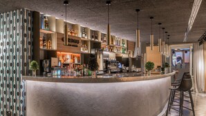 Un área de bar moderna con una barra curva, estantes con botellas y lámparas colgantes.