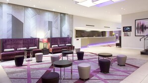 A modern lobby with a reception desk, seating area, and a patterned carpet.