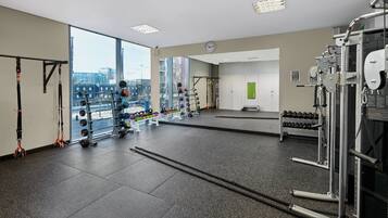 A gym with various exercise equipment, large windows, and a view of the city.