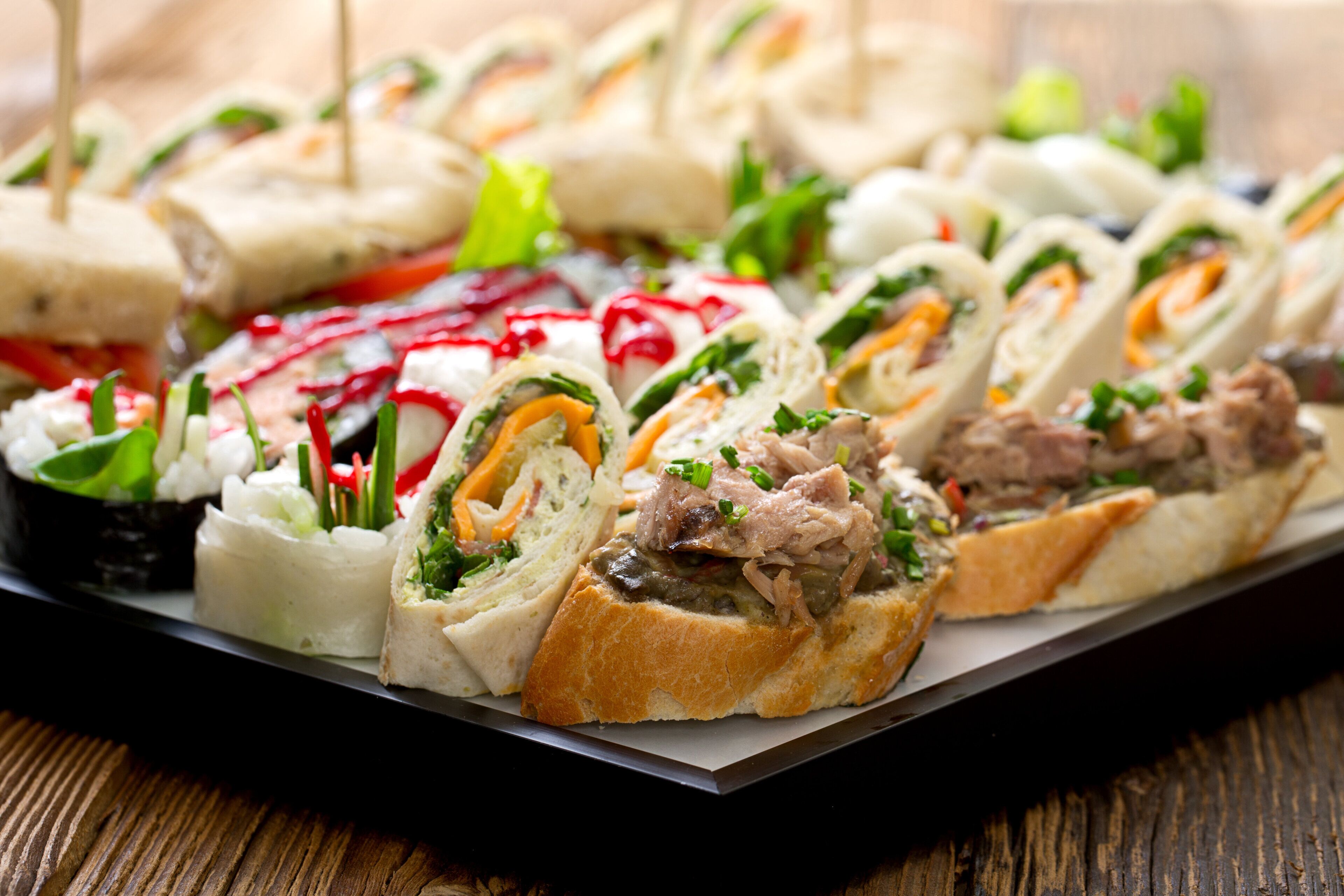A variety of sandwiches and salads on a tray.