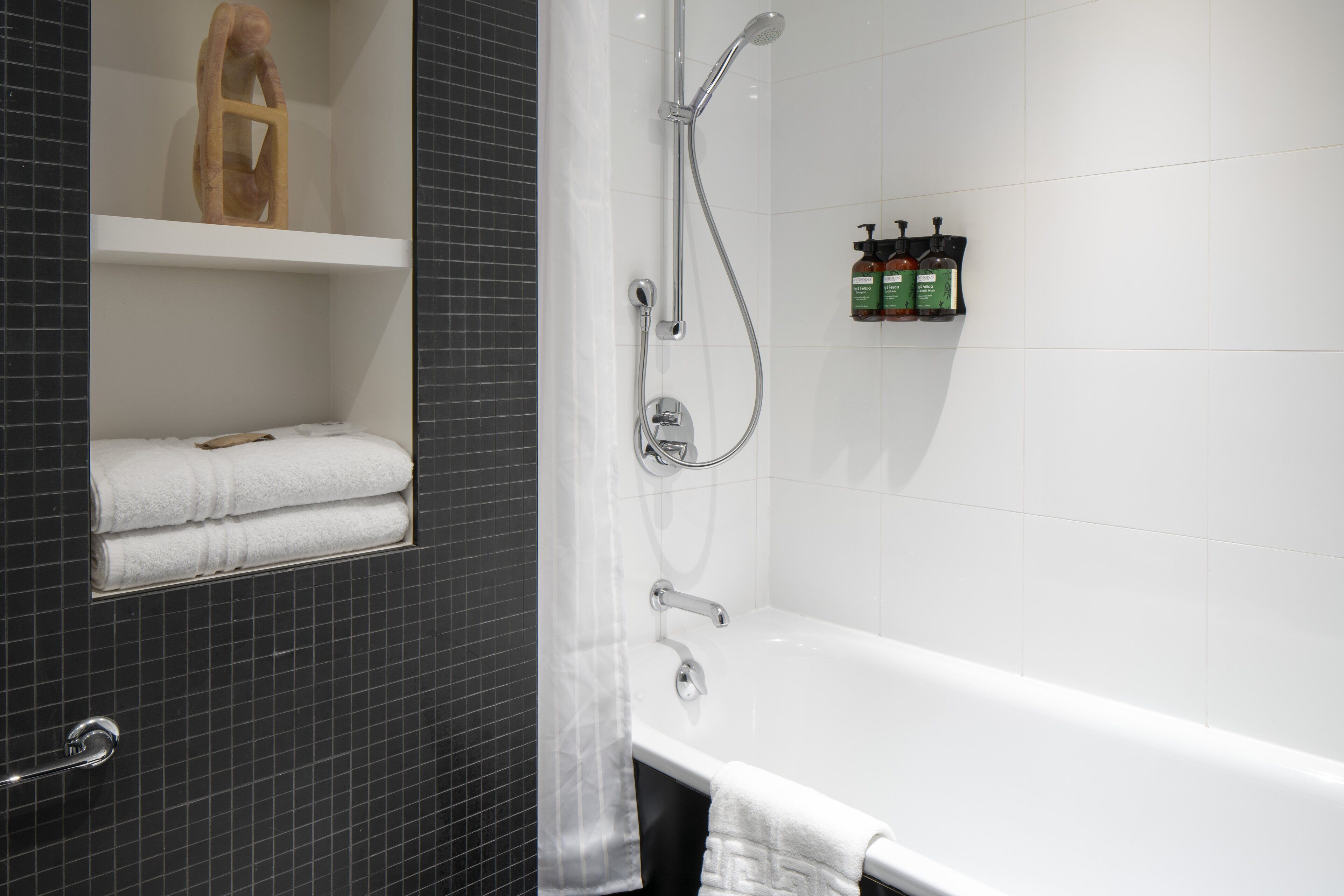 Un bagno moderno con una vasca, una doccetta e uno scaffale con articoli da toilette.
