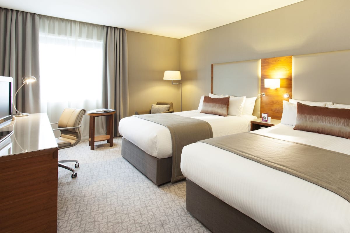 Een hotelkamer met twee bedden, een bureau, een stoel, een lamp en een nachtkastje.