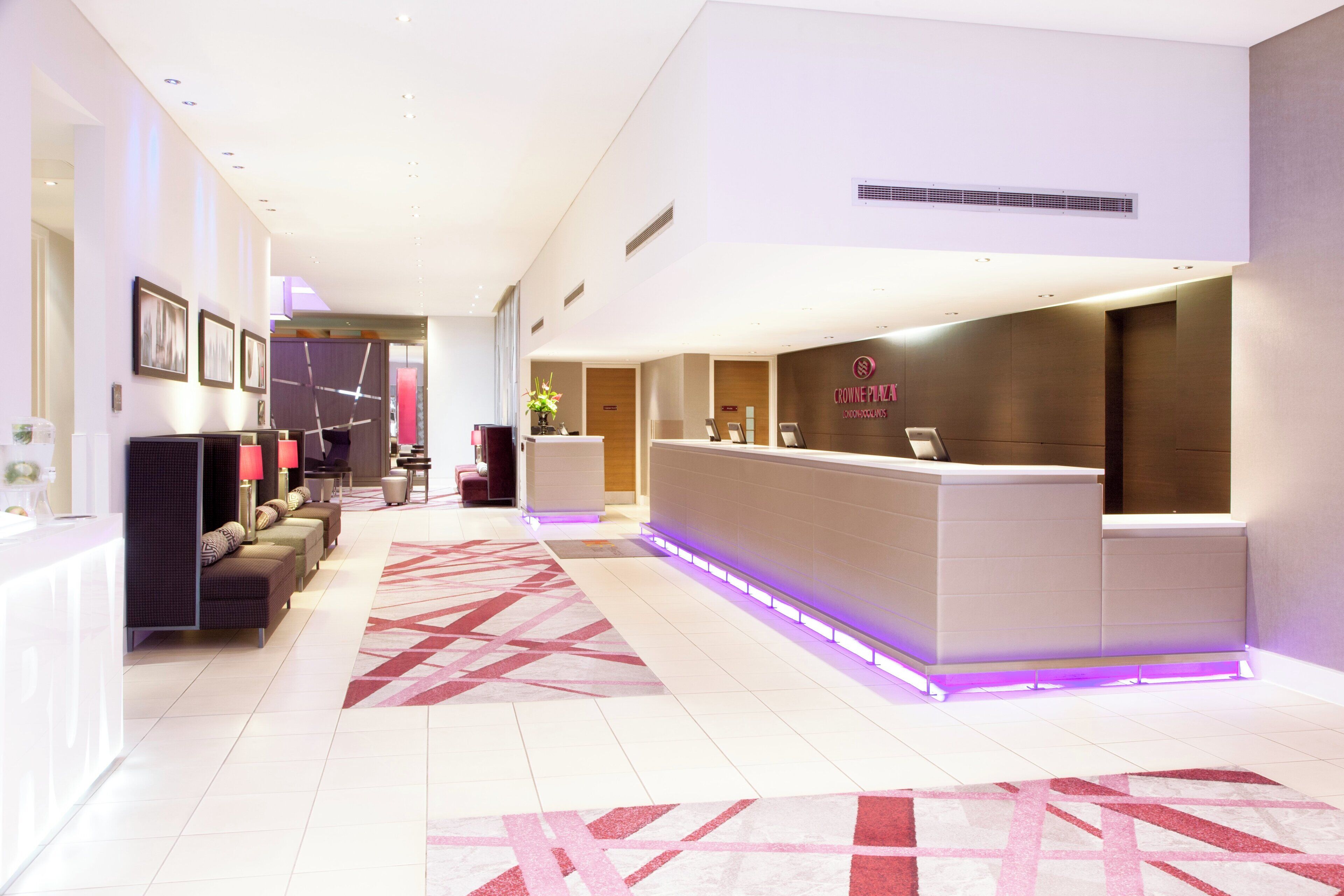 A hotel reception area with a reception desk, seating area, and a decorative rug.