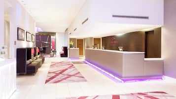 A hotel reception area with a reception desk, seating area, and a decorative rug.
