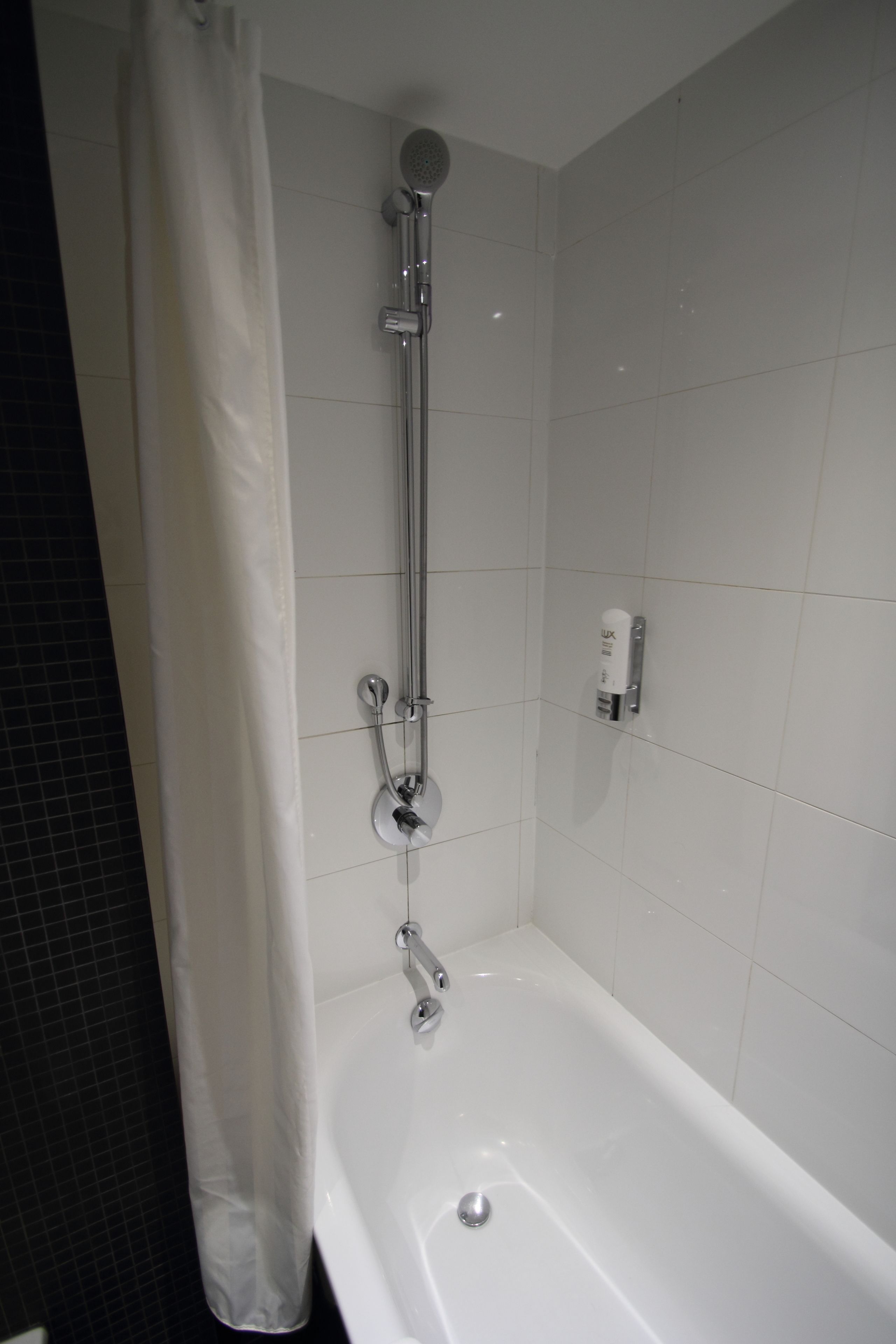 Ein Badezimmer mit Badewanne, Dusche und einem weißen Vorhang.