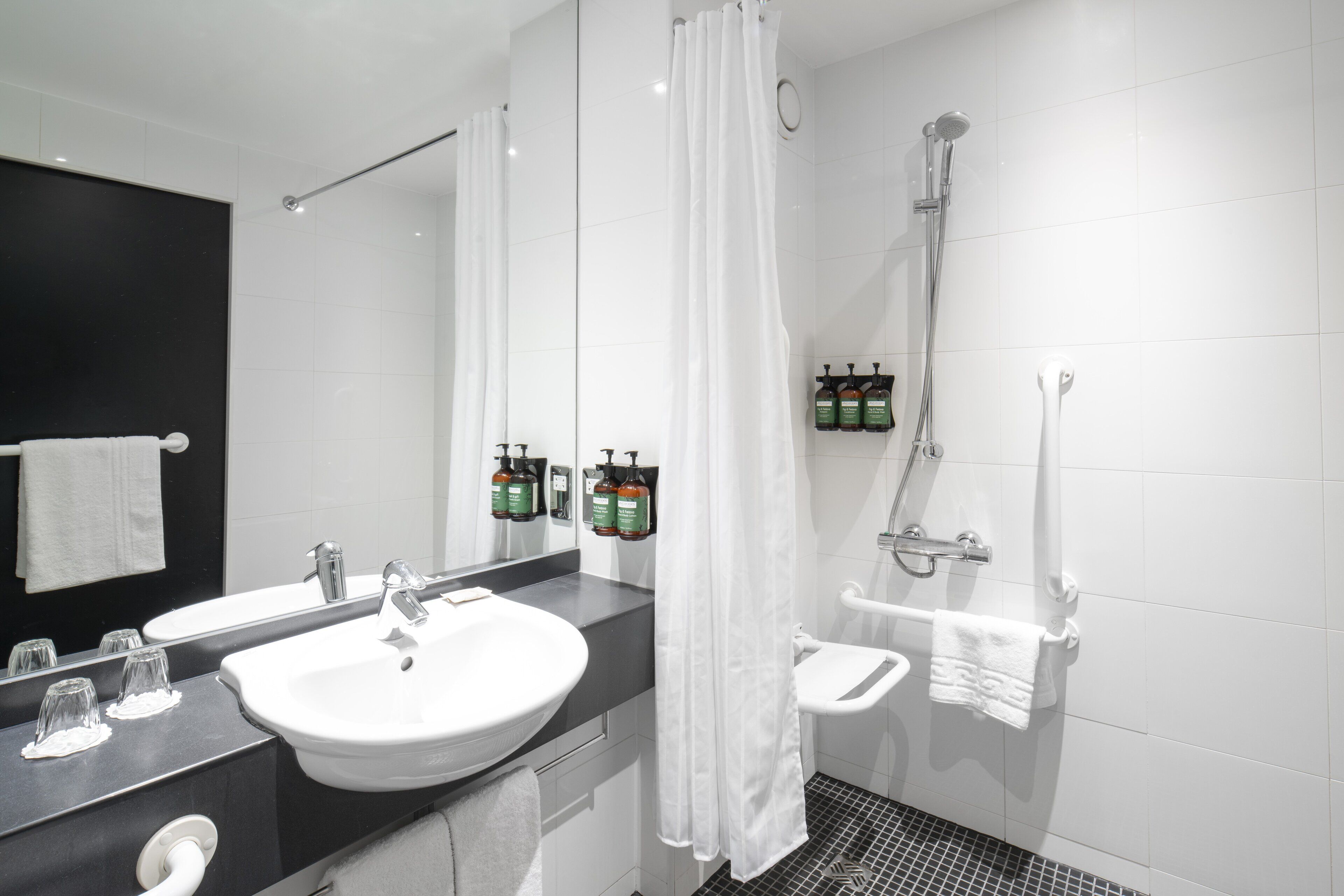 Un baño moderno con un lavamanos grande, un espejo, una ducha y artículos de tocador en la pared.