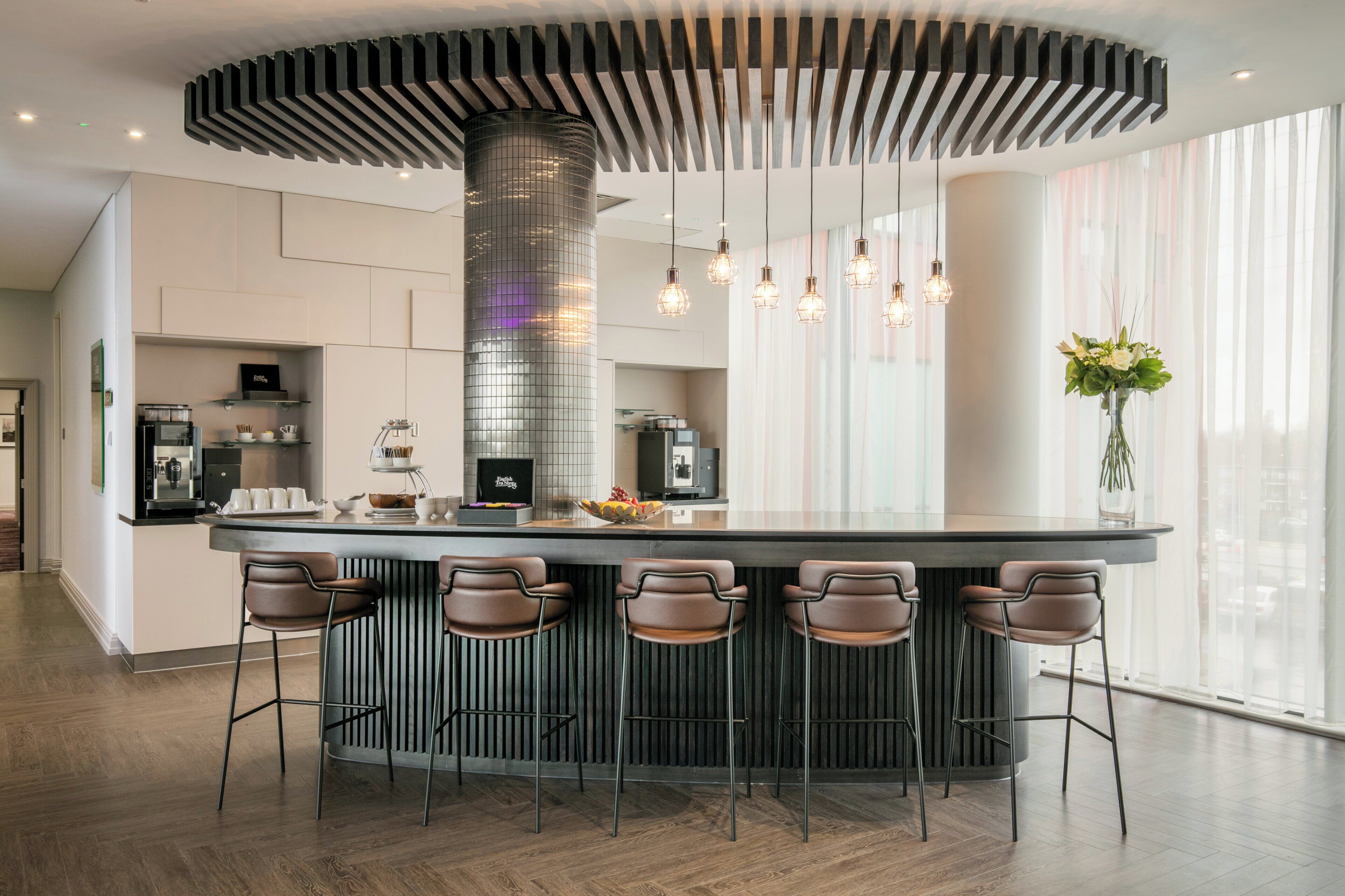 A modern kitchen with a central island, bar stools, and pendant lighting.