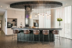 A modern kitchen with a central island, bar stools, and pendant lighting. - Crowne Plaza London - Docklands by IHG (London)