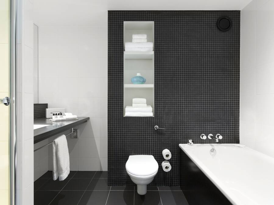Uma casa de banho moderna com sanita branca, banheira e um armário com artigos de higiene pessoal.