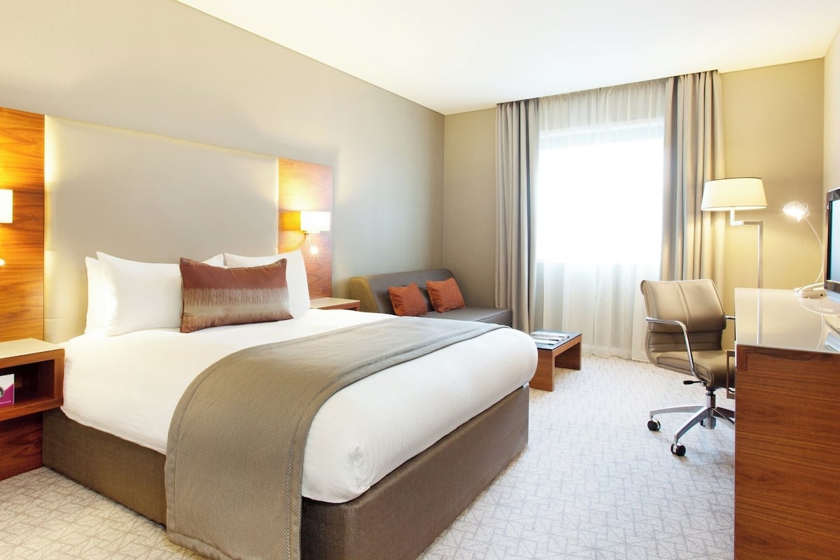Een hotelkamer met een groot bed, nachtkastjes, een bureau, een stoel en een televisie.