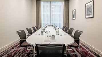 A conference room with a long table, chairs, water bottles, and framed pictures on the walls.