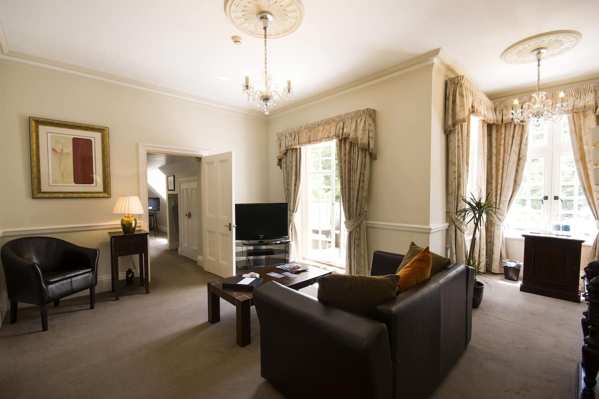 A living room with a sofa, a television, a lamp, and a chandelier.