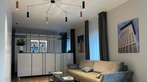 Een moderne woonkamer met een bank, een glazen salontafel en een hanglamp.