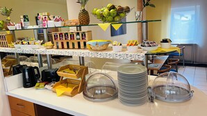 Een buffetopstelling met diverse gerechten, waaronder fruit, drankjes en sauzen.