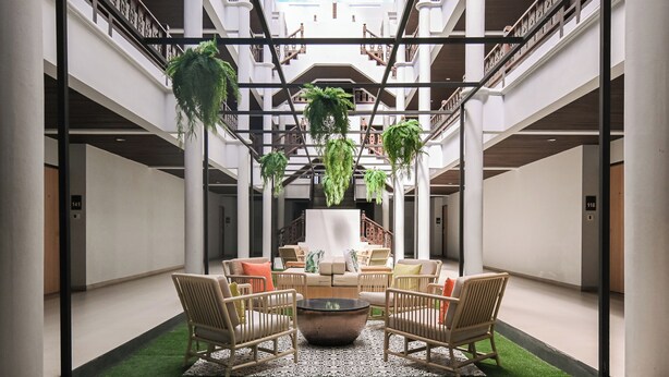 Een ruime atrium met een centraal zitgedeelte, meerdere verdiepingen en hangende planten.