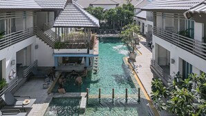 Een resort met een centraal gelegen zwembad, verbonden met meerdere gebouwen met balkons.