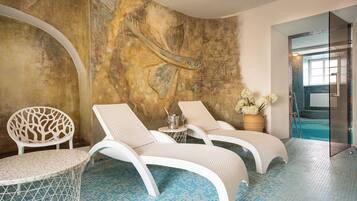 Relax by the serene indoor pool surrounded by a modern aesthetic, comfortable lounge chairs, and a vibrant mural.