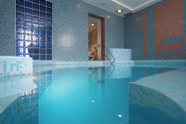 A swimming pool with a tiled interior and a glass wall. - Mabre Residence Hotel (Vilnius)