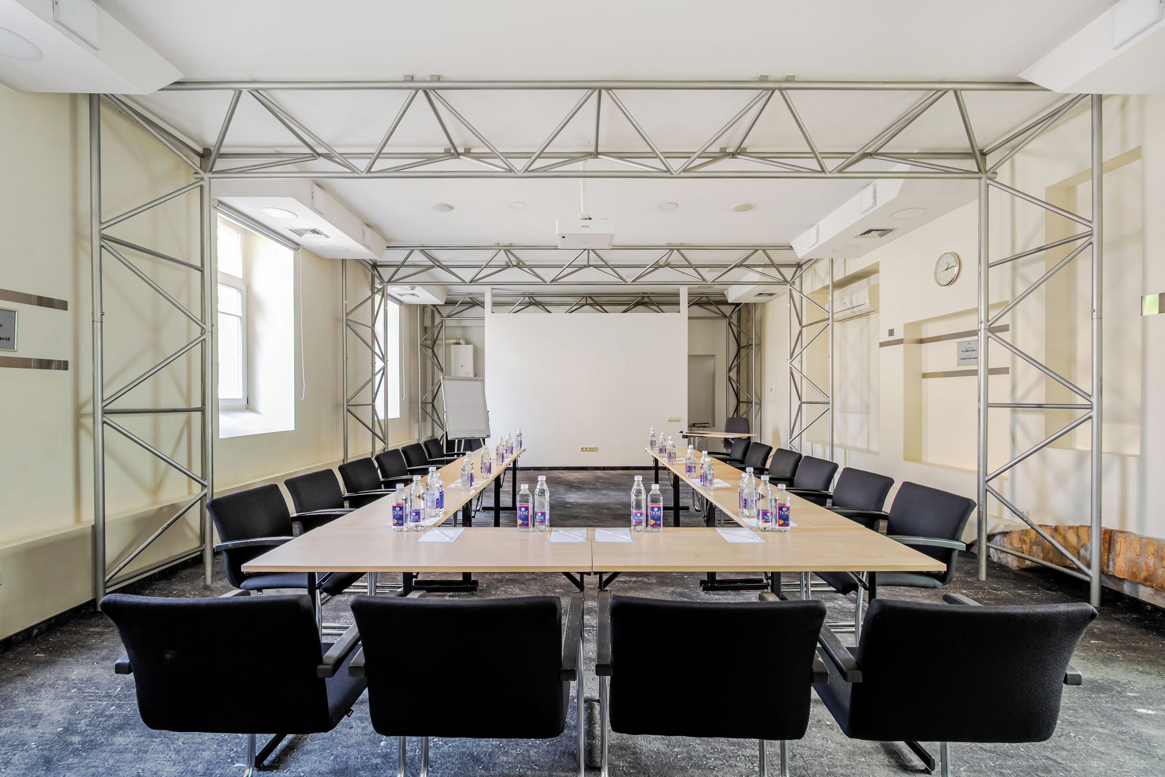 A conference room with a long table, black chairs, and water bottles.