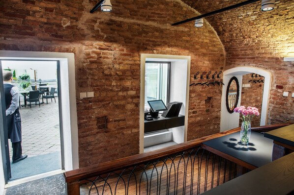 A reception area with a brick wall, a computer, and a vase with flowers. - Mabre Residence Hotel (Vilnius)