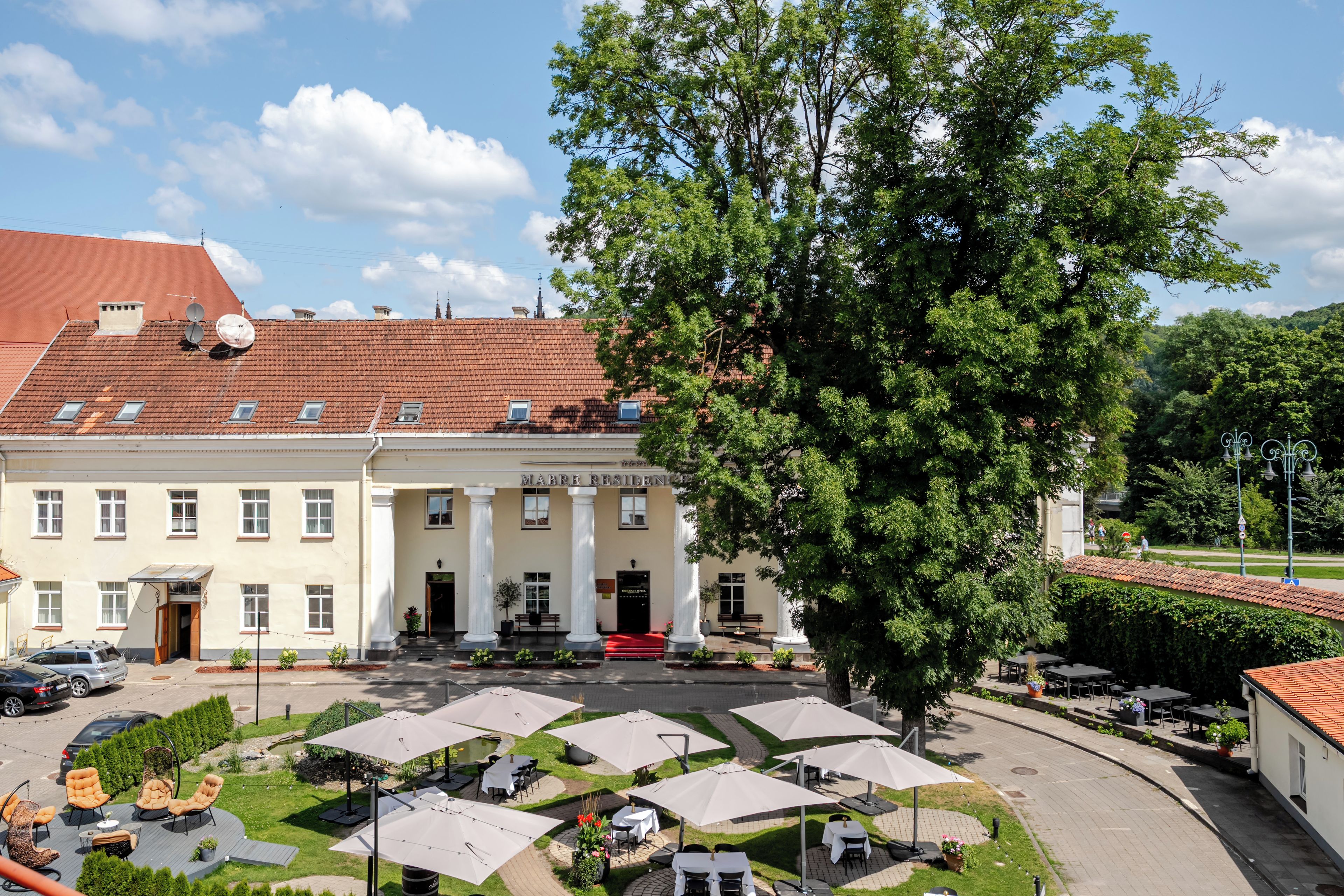 Un hôtel doté d’une cour intérieure, d’un espace extérieur aménagé et d’un grand arbre.