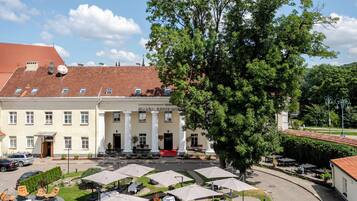 A hotel with a courtyard, outdoor seating, and a large tree.
