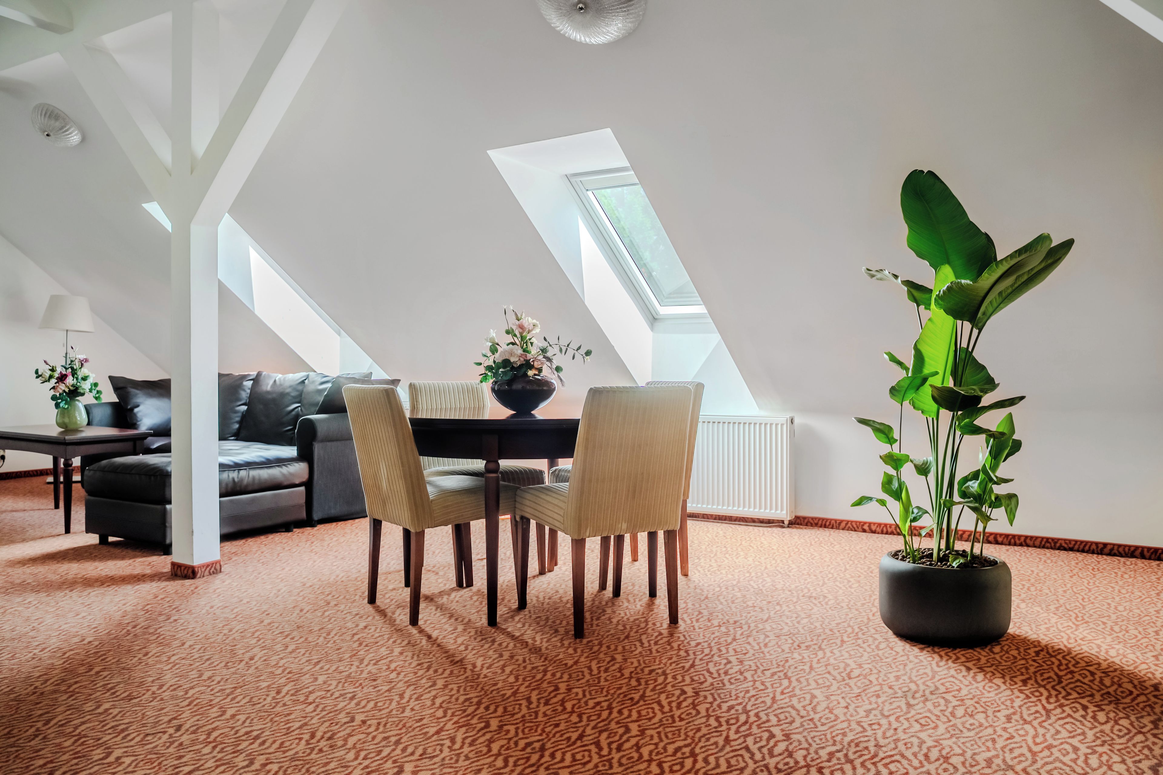 Un loft moderno con comedor, asientos y una gran planta en maceta.