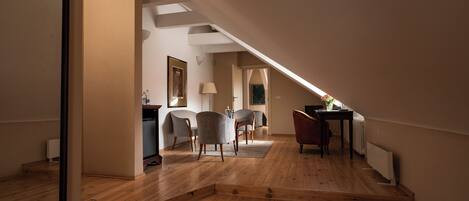 Un ampio loft con pavimento in legno, zona pranzo con sedie, un tavolo e un termosifone.