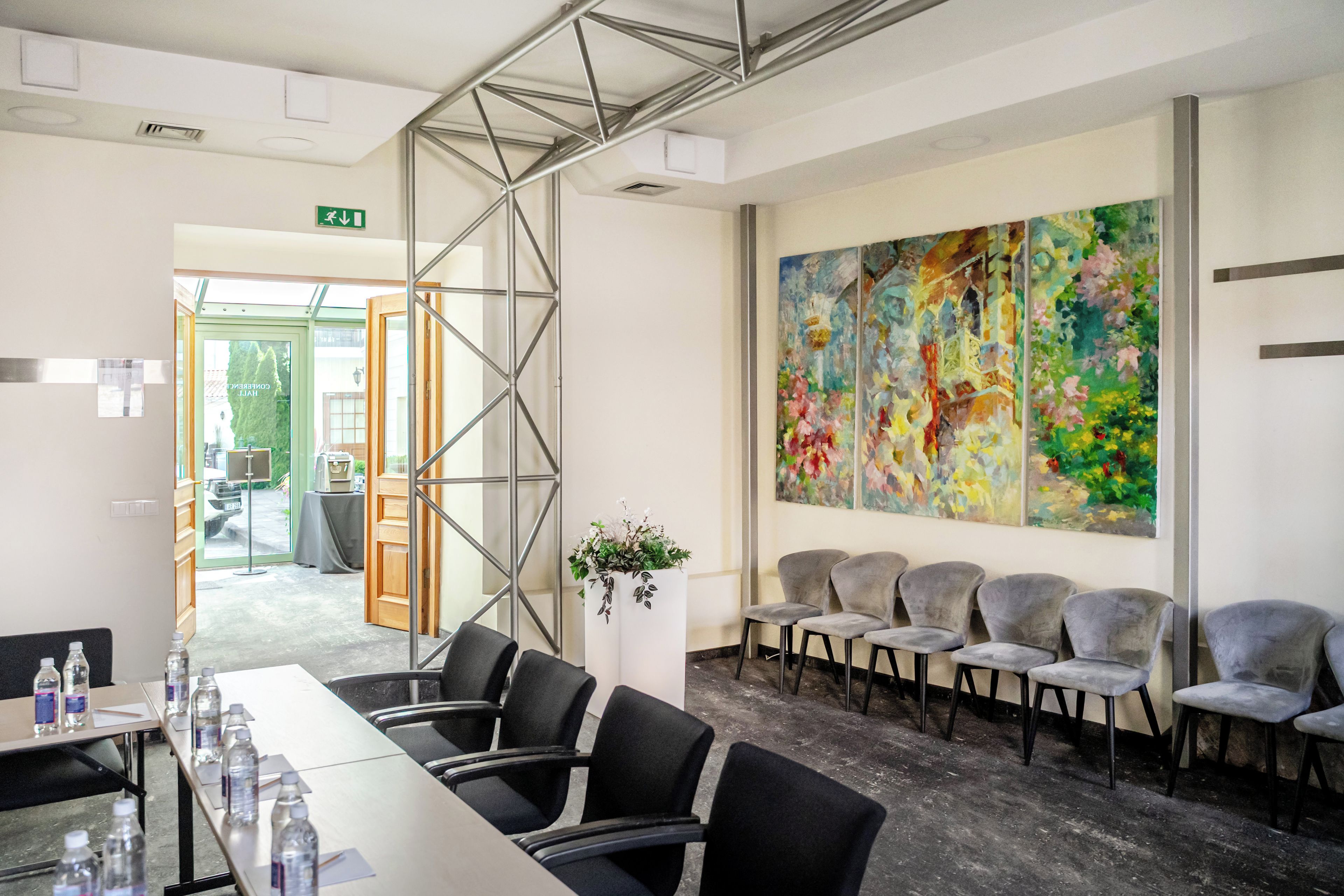 Une salle de conférence avec une longue table, des chaises, un grand tableau abstrait et un escalier.