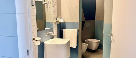 Un baño moderno con lavamanos, inodoro y zona de ducha.
