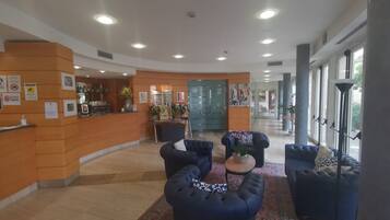 Una hall con reception, angolo salotto e ampie finestre.