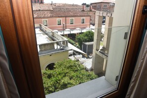 A view through a window with a view of a building with a tiled roof and a balcony. - Duca D'aosta (Mogliano Veneto)