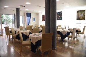 A dining area with round tables, chairs, and artwork on the walls.