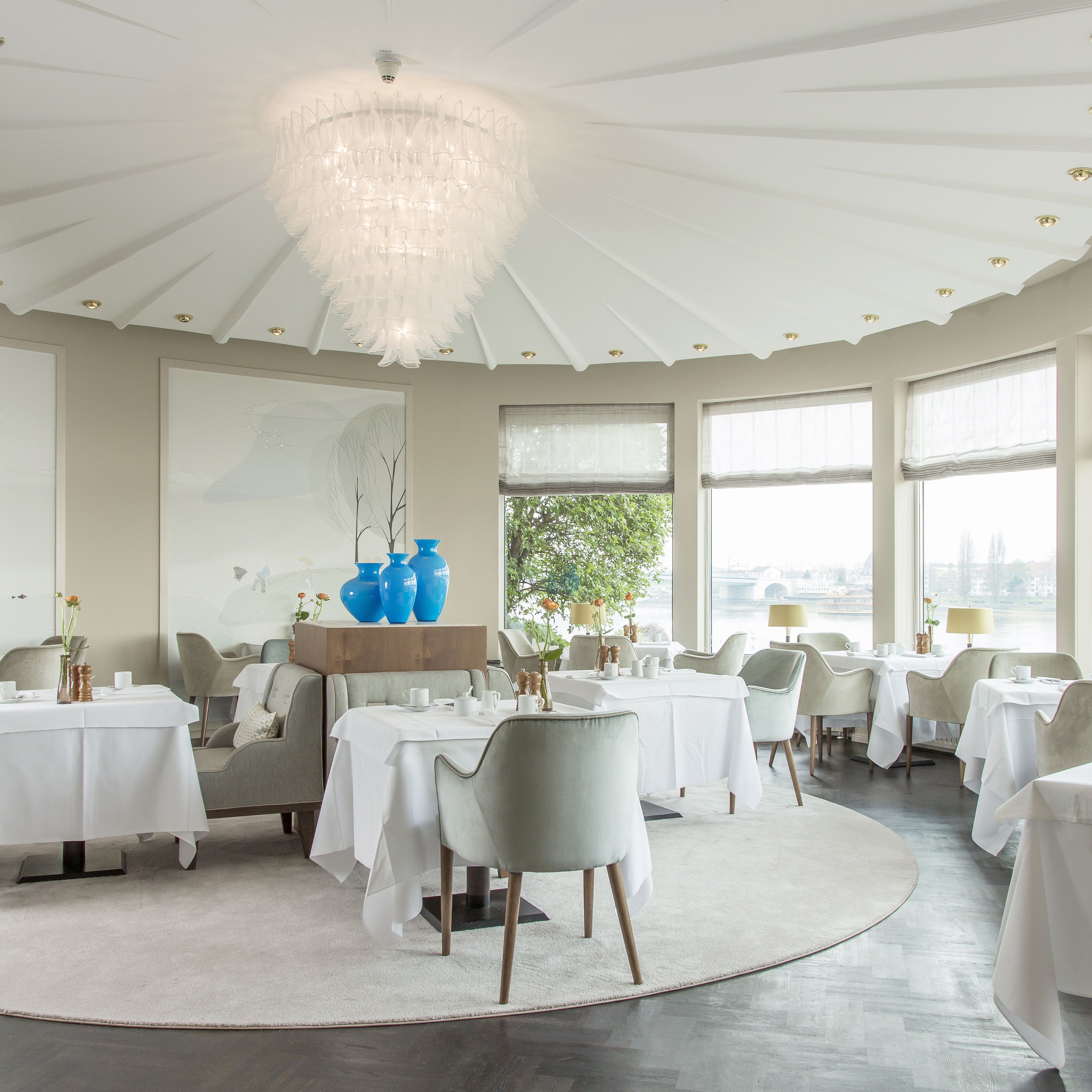 Un espace repas avec des tables rondes, des chaises et un lustre.
