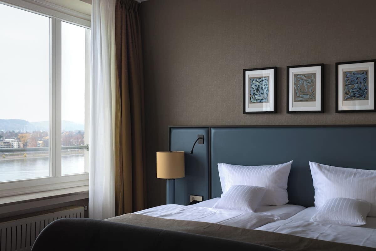 Une chambre d’hôtel avec un grand lit, une table de chevet avec une lampe et trois œuvres d’art encadrées accrochées au mur.