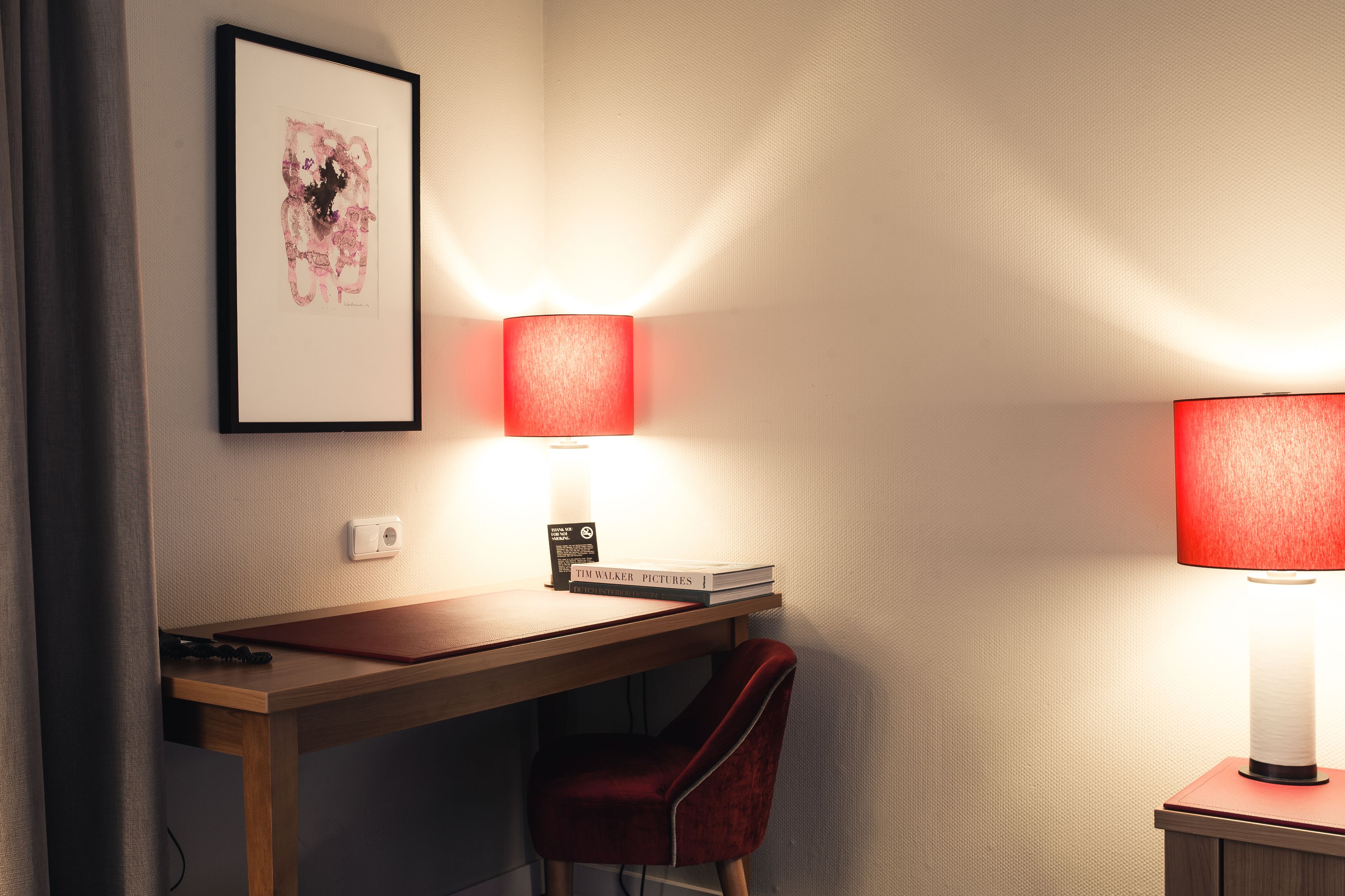 Un espacio de trabajo ordenado con un escritorio, una silla y dos lámparas fijadas a la pared.