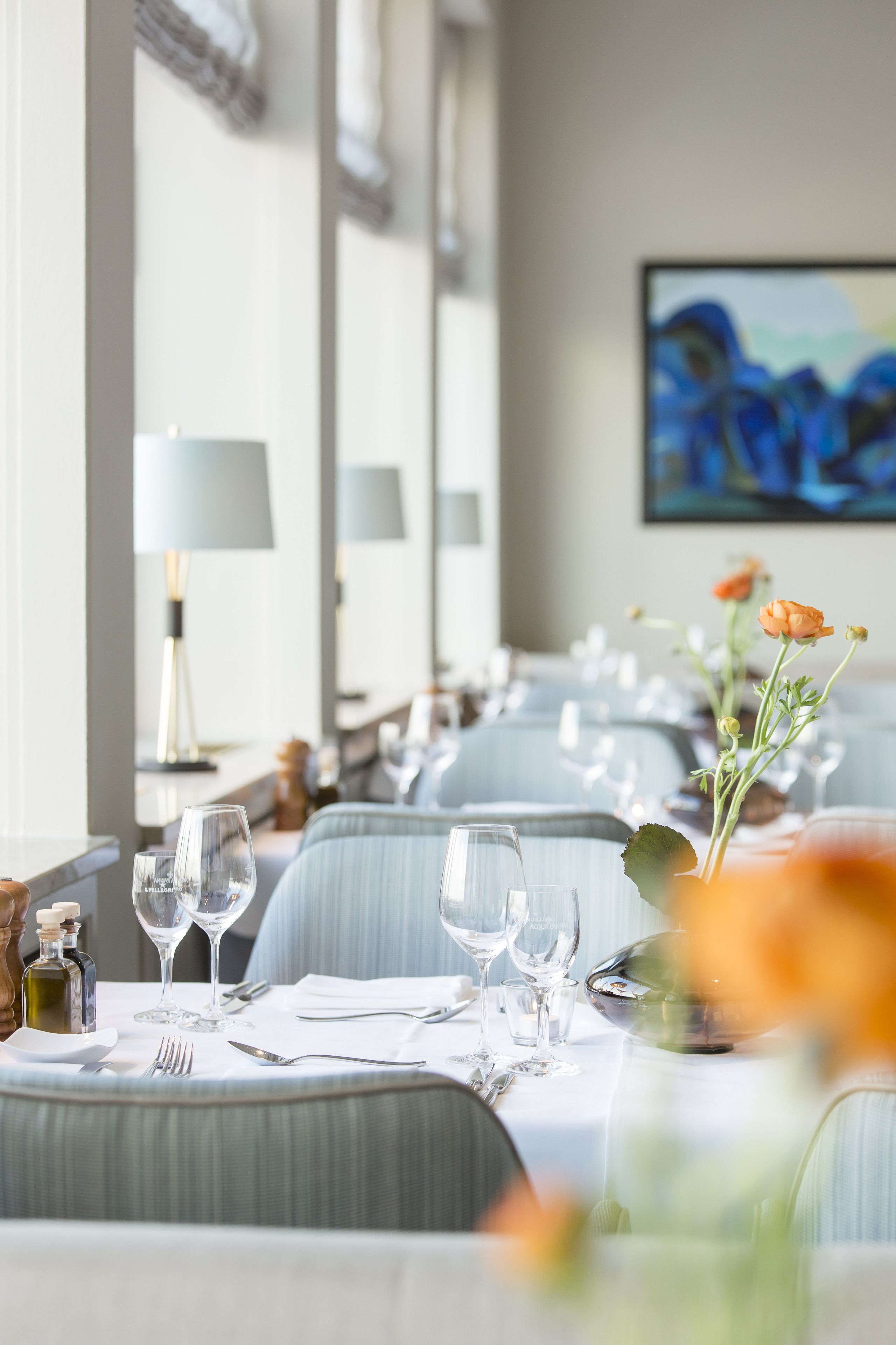 A dining area with tables set for a meal, including wine glasses and cutlery.