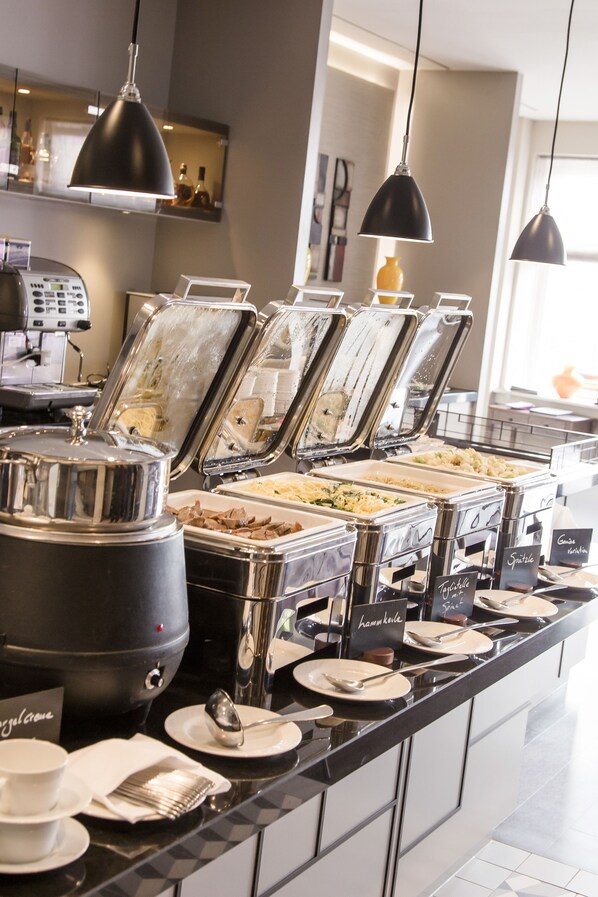 A buffet setup with various food containers and utensils.