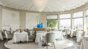 Un espace repas moderne avec des tables rondes, des chaises gris clair et une pièce décorative centrale.