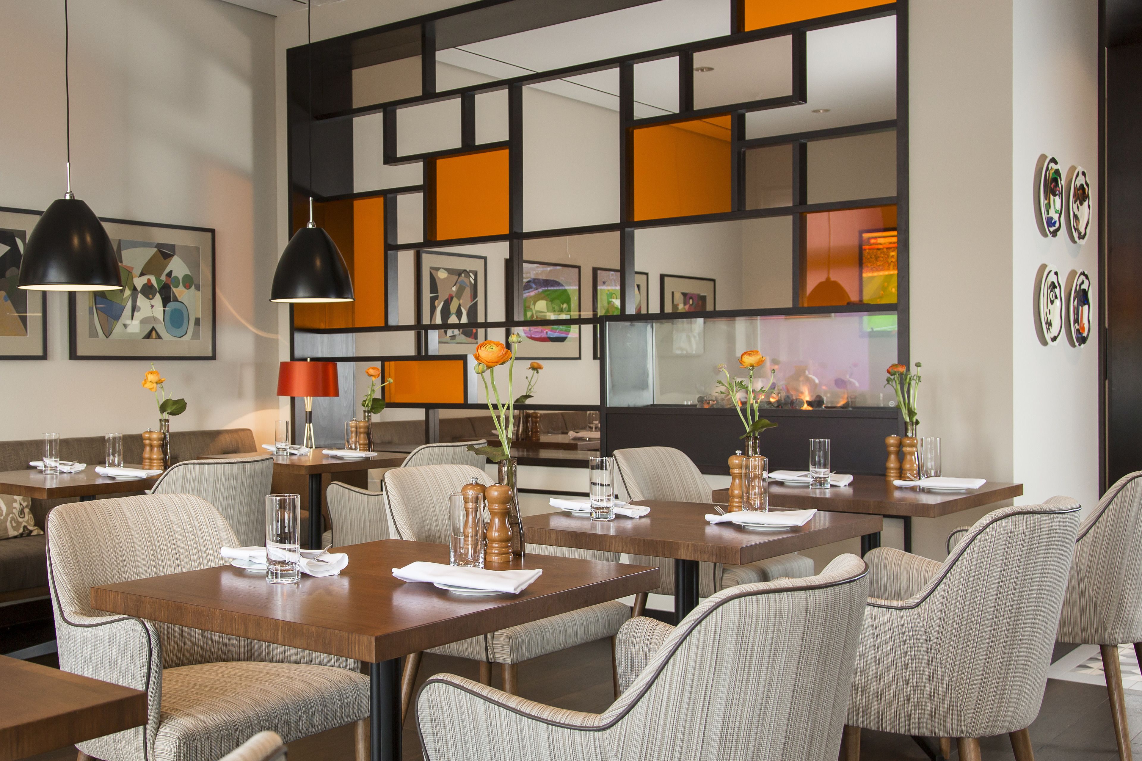 A modern dining area with rectangular tables, striped chairs, and pendant lighting.